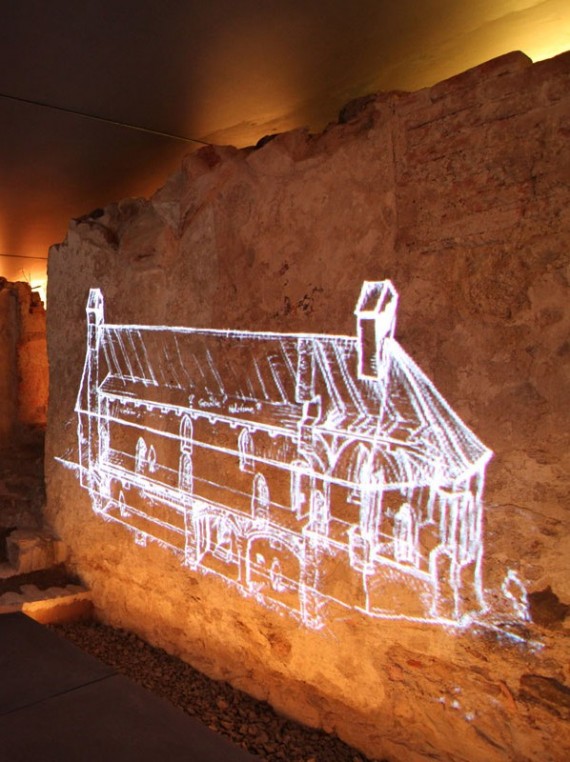 Im unterirdischen Schauraum: Projektion einer Skizze der Erasmuskapelle an altes Gemäuer, rötliche Beleuchtung suggeriert Feuer